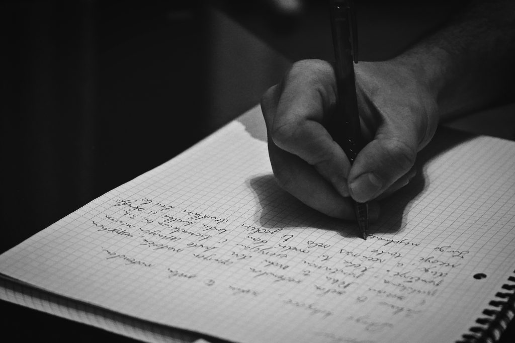 Person writing in a notebook with a pen